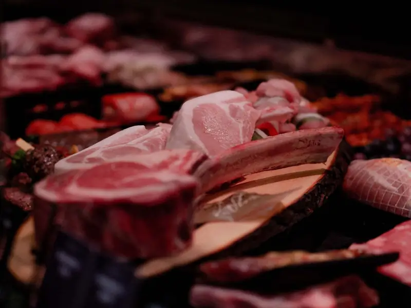 Raw pork and beef cuts on a wooden board at a market meat counter